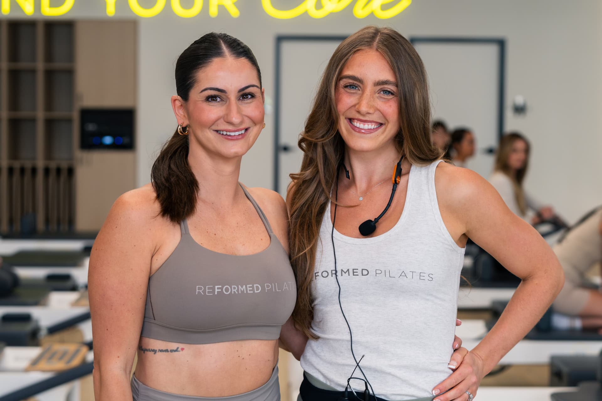 Two Reformed Pilates instructors smiling together in the studio